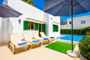 a patio with chairs and an umbrella and a swimming pool at Villa Binimelis in Cacla D'or