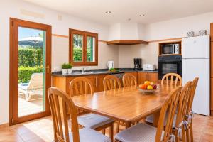 a kitchen with a wooden table and chairs at Villa Binimelis in Cacla D'or
