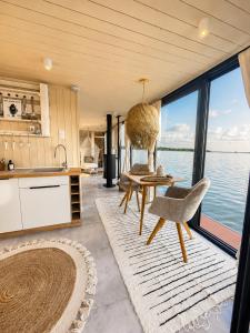 a kitchen with a table and chairs and the water at Bohéa Spa Hausboot mit Sauna und Kamin in Schwielochsee