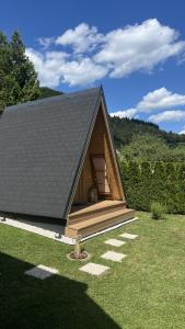 a small house with a black roof on a field at Castle view Chalet - ZemvaStays in Zgornje Gorje +6 photos