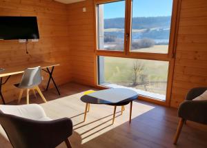 ein Zimmer mit Tisch, Stühlen und Fenstern in der Unterkunft L'esca'lac in Grande Riviere
