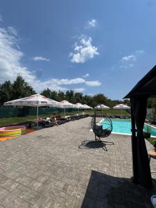 a group of chairs and umbrellas next to a swimming pool at Casa Logascu in Bîlta