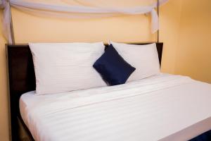 a bed with white and blue pillows on it at Sandton hotel kasese in Nalakonge