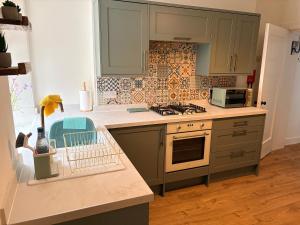 a kitchen with green cabinets and a stove top oven at Myrtlebank in Pitlochry