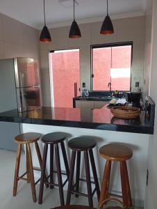 a kitchen with three bar stools at a counter at Casa da Serra in Serra Negra