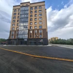 a tall building with a parking lot in front of it at Byrabau Tauwer in Shchūchīnsk