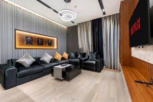 a living room with a black couch and a tv at Yas Island Luxury Apartment by City homes in Yas Island