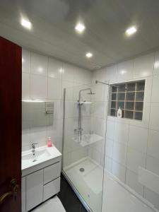 a white bathroom with a shower and a sink at Villa do Monte in Porto Moniz +35 photos