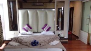 a bedroom with a large bed with purple pillows at Hotel Haven Intercontinental in Agartala