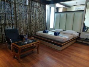 a bedroom with a bed and a chair and a table at Hotel Haven Intercontinental in Agartala