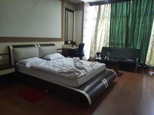 a bedroom with a bed and a chair and a table at Hotel Haven Intercontinental in Agartala