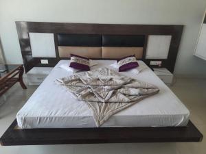a bedroom with a large bed with white sheets and purple pillows at Hotel Haven Intercontinental in Agartala