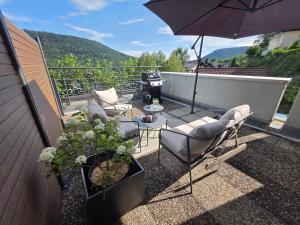 a patio with chairs and an umbrella and a grill at Calm Sun Apartment in Alpirsbach +16 photos