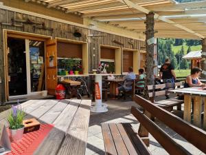 a patio with wooden benches and people sitting at tables at Gasthaus Klausen Ranch in Urnerboden