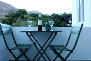 a table with two chairs and a bottle of wine at Lyra Apartments Tilos in Livadia +10 photos
