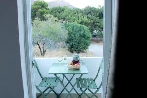 a table with wine glasses and a bowl of fruit on a balcony at Lyra Apartments Tilos in Livadia
