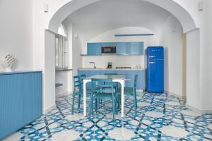a kitchen with blue cabinets and a table and chairs at Maison Blu Royal in Amalfi