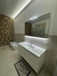 a bathroom with a sink and a mirror and a toilet at Villa Maria Marcella in Porto Santo Stefano