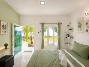 a bedroom with a green bed and a sliding glass door at Ava Beach Pakbara in Ban Pak Ba Ra
