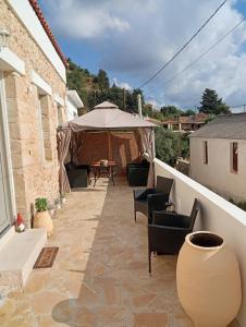 a patio with chairs and a table and an umbrella at Stone Villa Aori in Pemónia