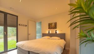 a bedroom with a large bed and a large window at Forest Lodge 6 persons #624 in Maasbree +10 photos