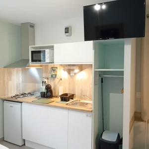 a small kitchen with white cabinets and a microwave at Weaky what you want in Ugine