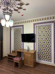 a living room with a tv and a wall with patterns at Amina Hotel PREMIUM in Bukhara
