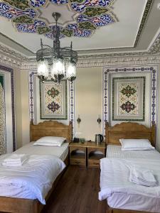 a bedroom with two beds and a ceiling with a chandelier at Amina Hotel PREMIUM in Bukhara +58 photos
