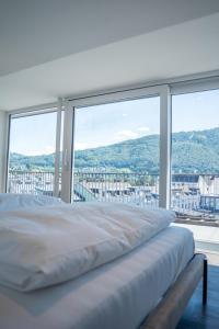 a white bed in a room with a large window at DAS ANTON - Penthouse mit Seeblick und kostenloser Garage in Gmunden