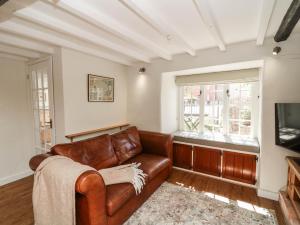 a living room with a leather couch and a television at Freya's Cottage in Lincoln