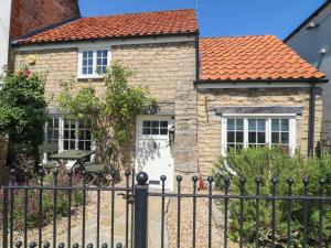 a stone house with a fence in front of it at Freya's Cottage in Lincoln