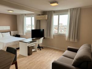 a hotel room with a bed and a desk with a television at Swan Rio Grande in Rio Grande