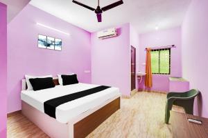 a bedroom with purple walls and a bed and a chair at Hotel O Royal Midlaans in Kālapettai +22 photos
