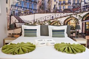 ein weißes Bett mit grünen Kissen und Aussicht in der Unterkunft Famous Crows Lisbon Suites in Lissabon + 91 Fotos