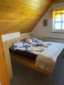 a bed in a room with a wooden ceiling at Chata u lesa in Výprachtice