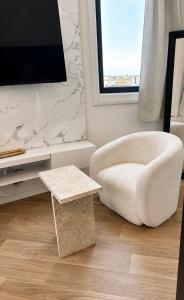 a living room with a white chair and a table at Mendess suites in Palaiseau