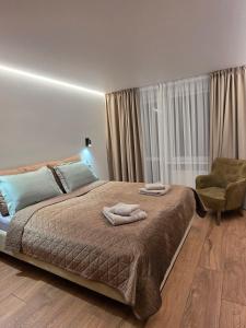 a bedroom with a large bed and a chair at Central Apartament in Telšiai