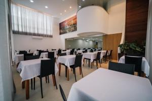 a dining room with white tables and chairs at Varadero Palace Hotel in Florianópolis