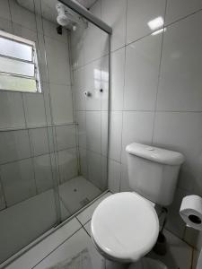 a white bathroom with a toilet and a shower at Pousada Vila Pitanga in Santos