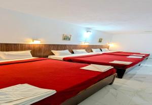 three beds in a room with red sheets at The Lantana Resorts in Madikeri