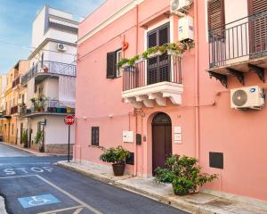 a pink building on a city street with a stop sign at Airport Palace Cinisi in Cinisi