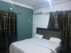 a bedroom with a bed and curtains in a room at Naira & Kobo Hotel and suite in Umuahia