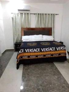 a bedroom with a large bed with aance versace versigun at Naira & Kobo Hotel and suite in Umuahia