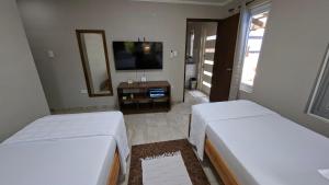 two beds in a room with a tv and a mirror at SEMEREL APARTMENT in Palm-Eagle Beach