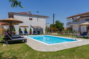 a swimming pool in a yard with chairs and umbrellas at Vila Petro in Evkarpía