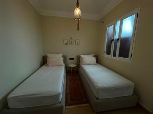 two beds in a small room with a window at appartemment essaouira in Essaouira