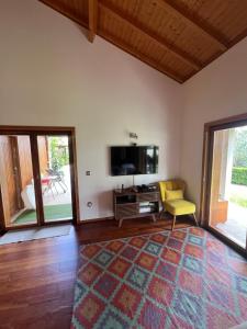 a living room with a tv and a yellow chair at Casa dos Cinco - Gerês in Terras de Bouro