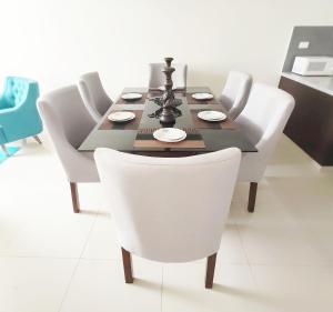 a dining room table with white chairs and a black table at Casa Barcelona in Santa Cruz de la Sierra