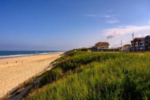 a beach with buildings and the ocean and grass at Les Tiny d'Aureilhan avec Jacuzzi privatif in Aureilhan