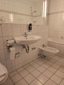 a white bathroom with a sink and a toilet at Hotel Zur Buche 24h Check-in, Free in Bockhorn